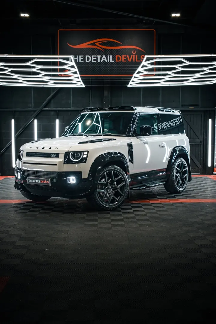 Land Rover Defender in sand and black, front three-quarter