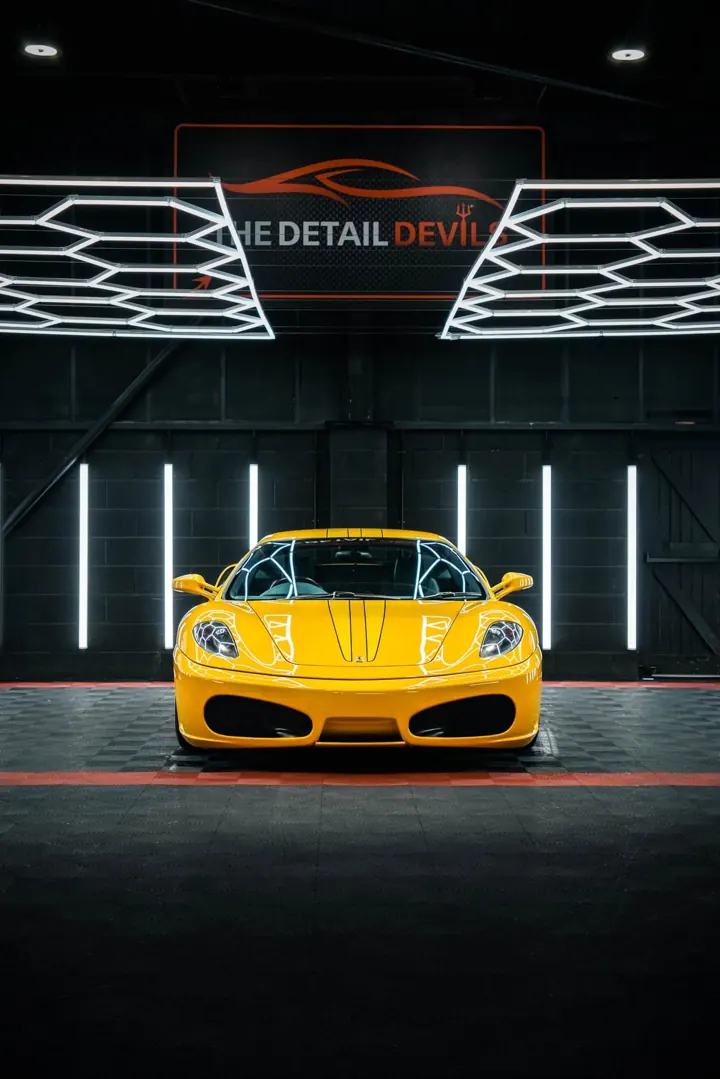 Yellow Ferrari F430 head-on beneath the unit's lights and sign