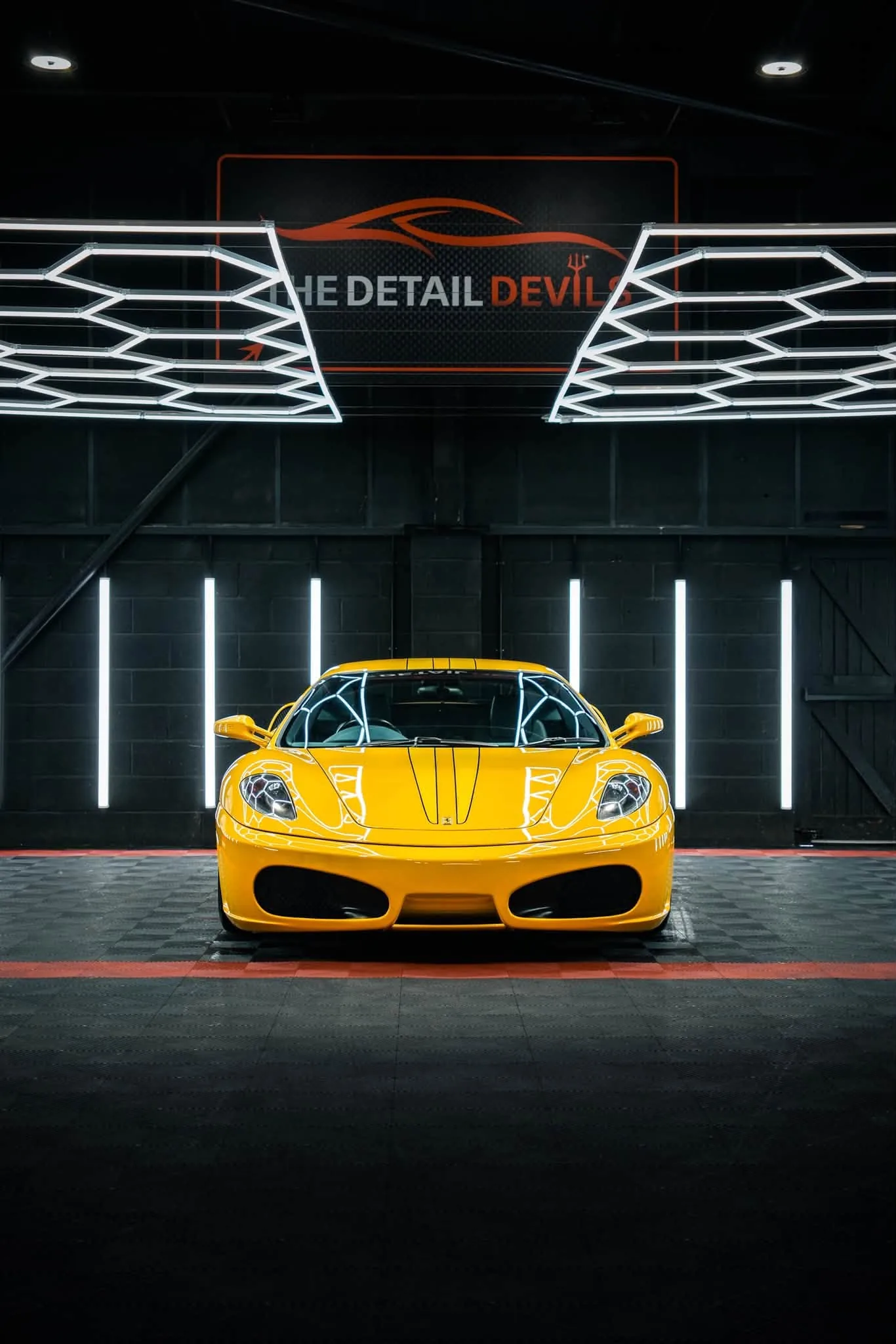 Ferrari F430 under the hexagon lights inside The Detail Devils unit in Bridgend