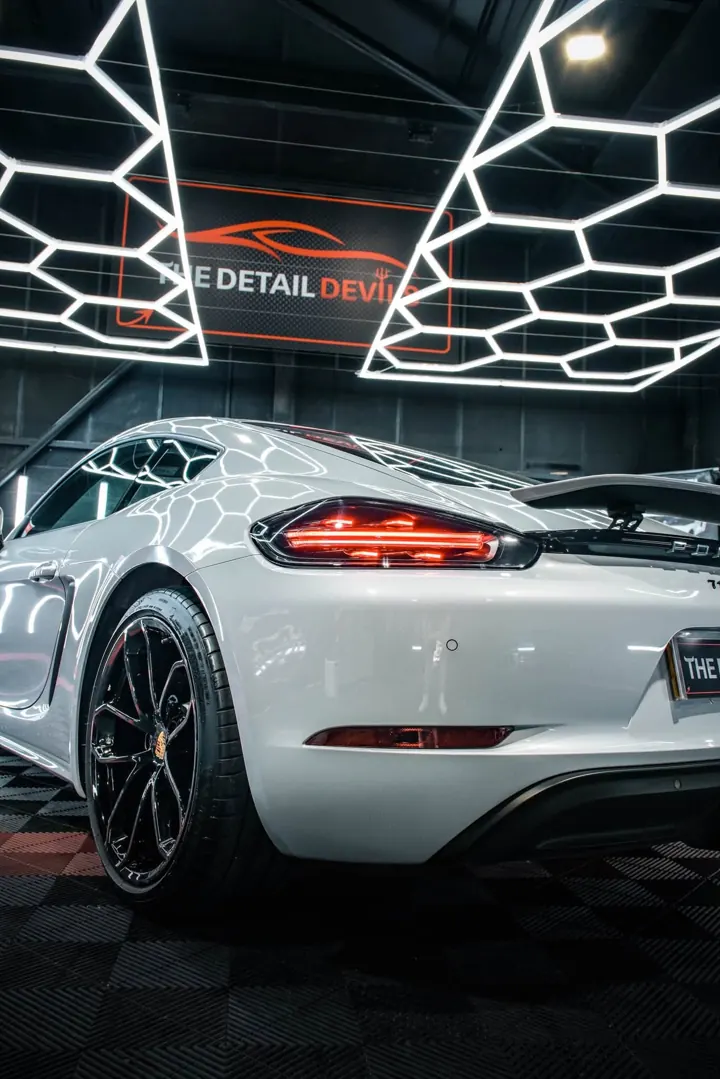 White Porsche 718 rear quarter, hex lights reflected in the paint