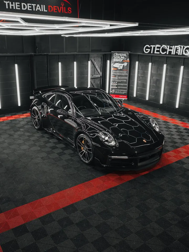 Black Porsche 911 Turbo S three-quarter view under hexagon lights